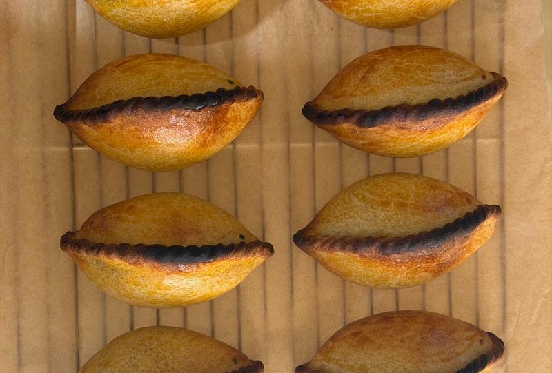 Eight salteñas cooling on a rack