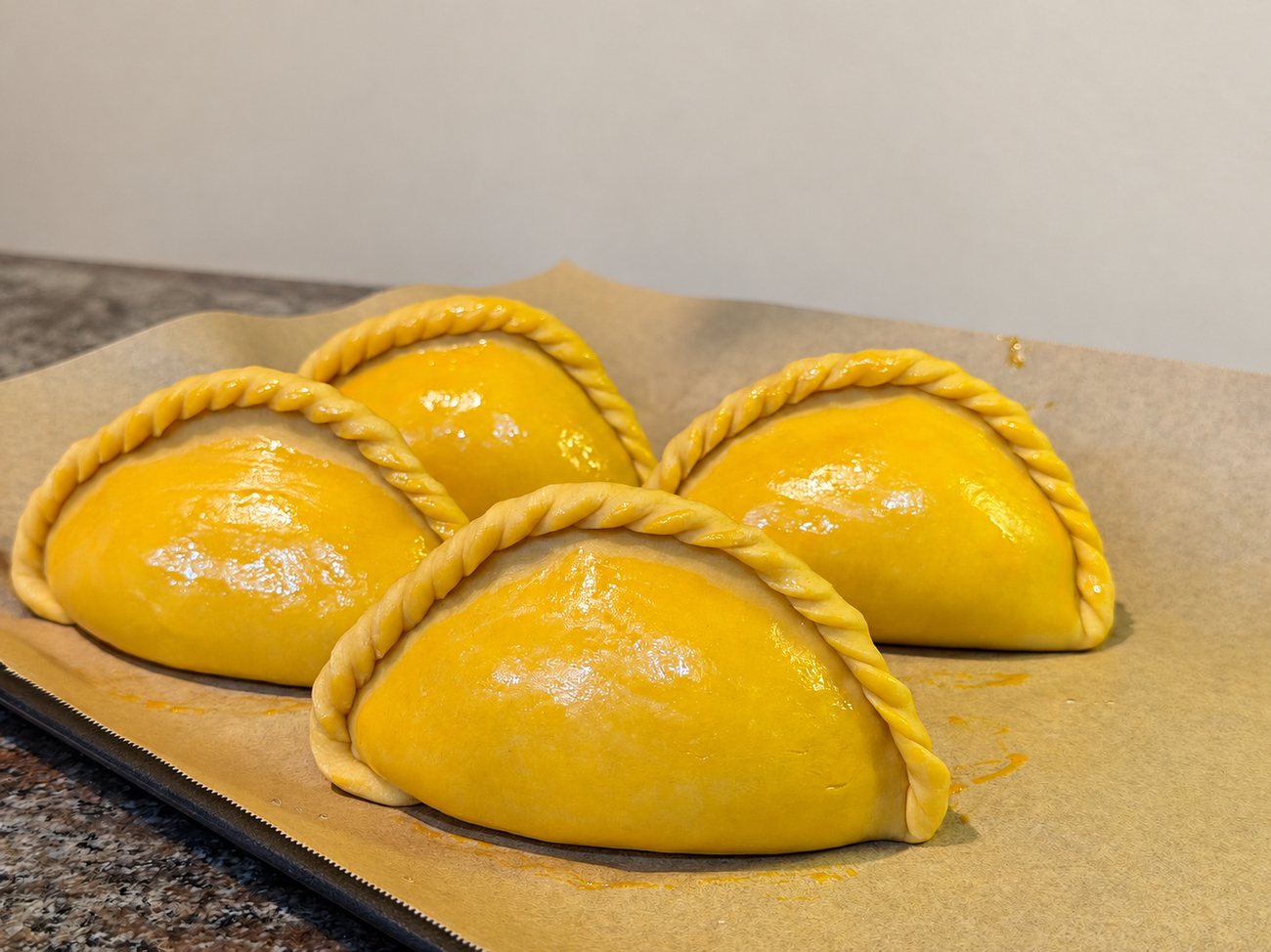 Unbaked salteñas spaced on a baking sheet